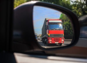 A red truck reflected in a car's side mirror