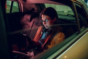 A female passenger uses her smartphone in a Lyft car.