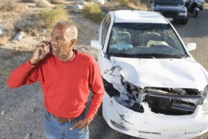 A man makes a phone call at the scene of a collision to ask a car accident lawyer how long a car accident settlement takes.