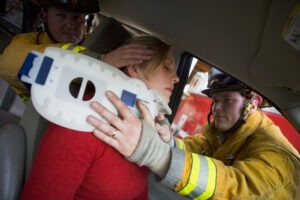 Emergency responders help an injured female driver out of the vehicle after a crash. A personal injury lawyer can tell you more about what to expect physically after a car accident.